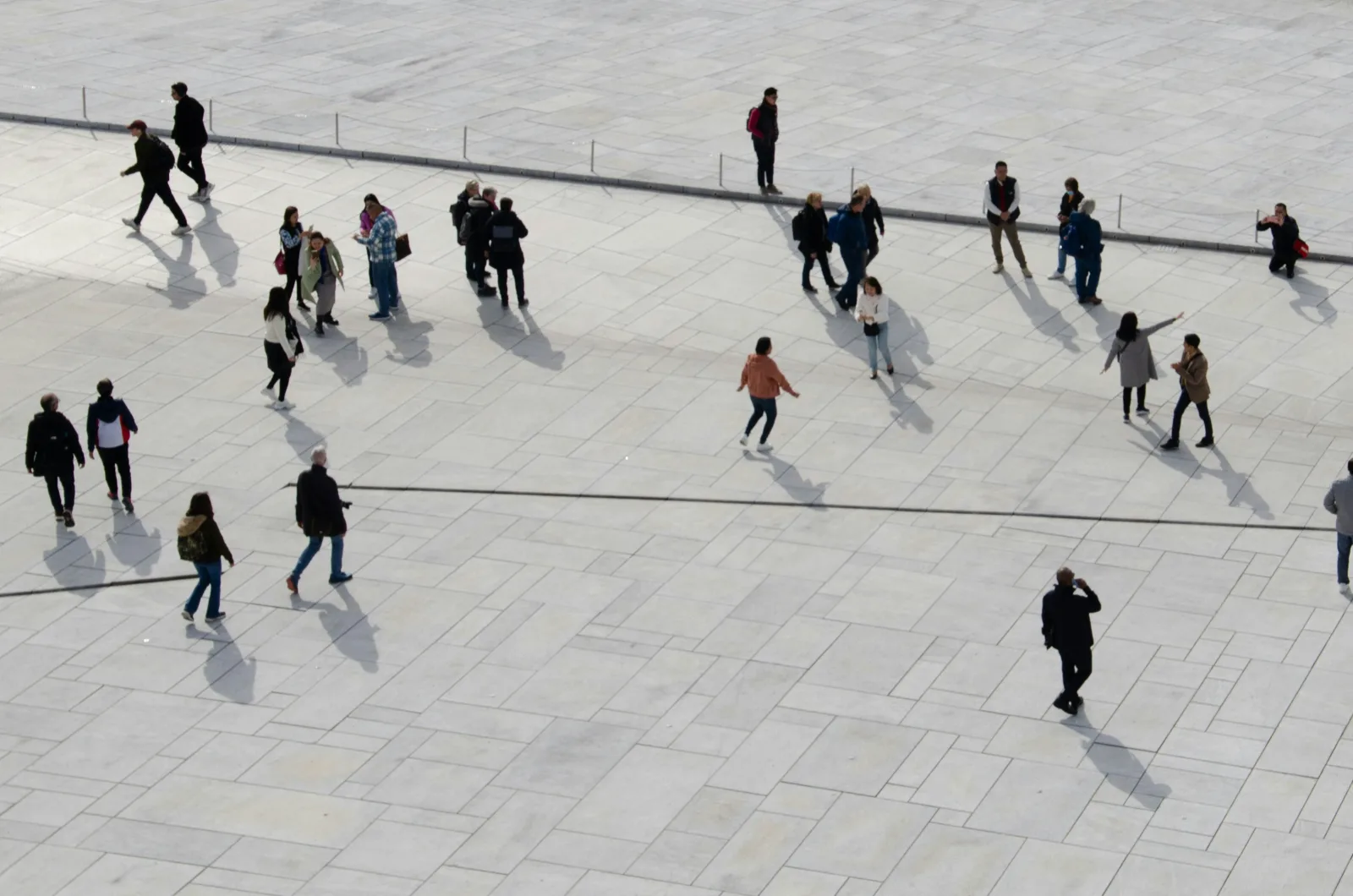 People crossing a stone plaza, seen from above